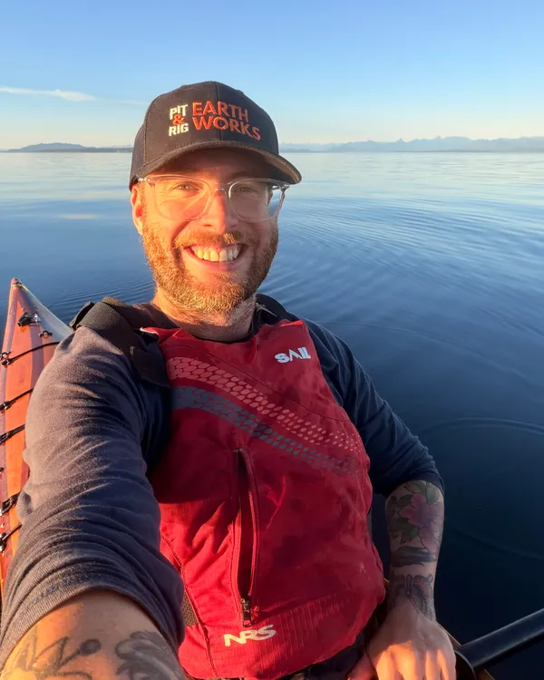 JP, the founder of Buns&Roll, smiling in a kayak on calm water